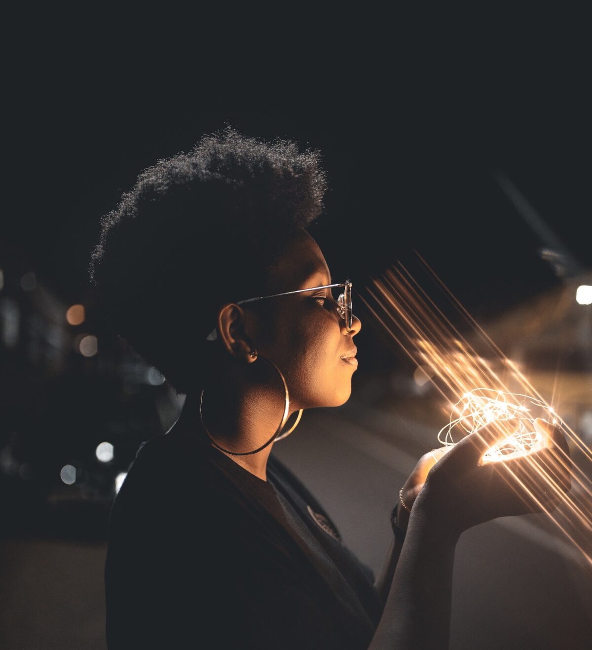 Young woman meditating with a string of lights in her hand