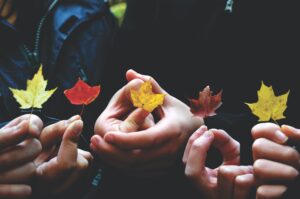 Five Hands holding an autumn leaf